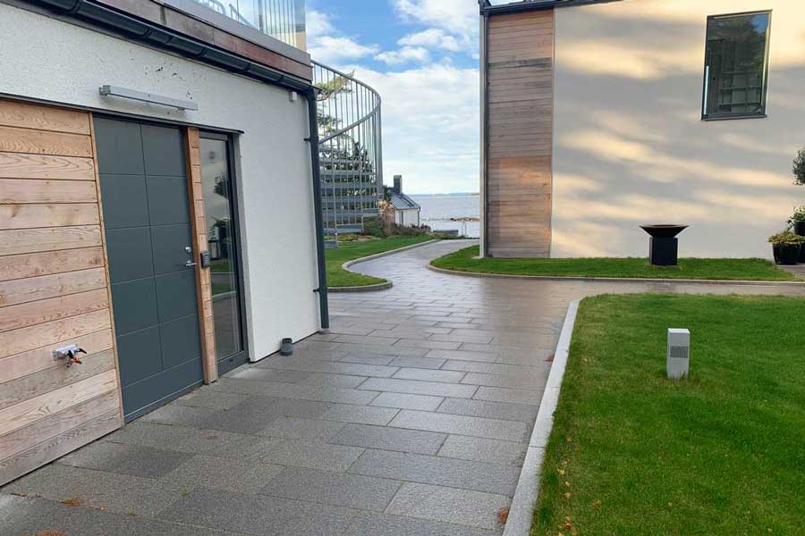 En g&aring;ng med plattor bredvid ett tr&auml;hus